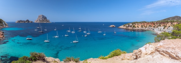 Panorama de Cala Hort com iates à vela de mar e a montanha Es Vedra. Ibiza, Ilhas Baleares. Espanha