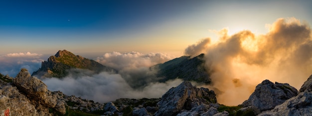 Panorama der Berge mit den roten Wolken der untergehenden Sonne