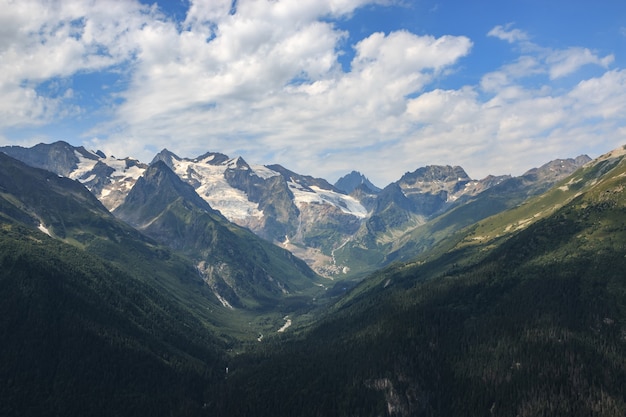 Panorama der Bergszene mit dramatischem blauem Himmel im Nationalpark von Dombay, Kaukasus, Russland. Sommerlandschaft und sonniger Tag