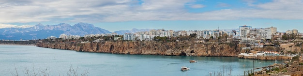 Panorama der Küste von Antalya mit einer großen Anzahl von Fünf-Sterne-Hotels, Palmenpromenade mit Booten, die im Meer und Bergen im Hintergrund segeln