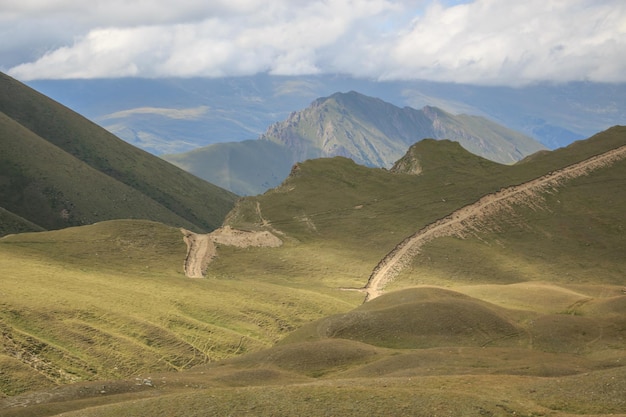 Panorama der Straße in den Bergen des Nationalparks Dombay, Kaukasus, Russland, Europa. Sommerlandschaft, Sonnenscheinwetter, dramatischer blauer Himmel und sonniger Tag