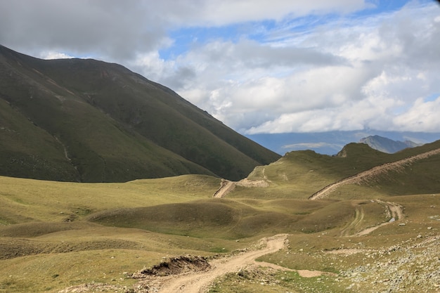 Panorama der Straße in den Bergen des Nationalparks Dombay, Kaukasus, Russland, Europa. Sommerlandschaft, Sonnenscheinwetter, dramatischer blauer Himmel und sonniger Tag