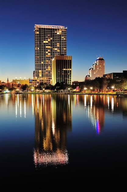 Panorama do horizonte do centro de Orlando sobre o Lago Eola à noite com arranha-céus urbanos e céu claro.