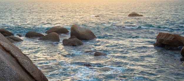 Panorama do mar com ondas batendo contra as rochas ao pôr do sol Seascape