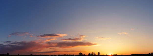 Panorama dramático do céu com nuvens ao pôr do sol. O sol se põe no horizonte.