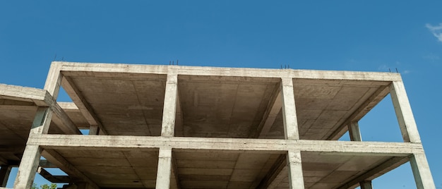 Panorama de un edificio residencial de varios pisos en construcción y grúa sobre un fondo de cielo azul