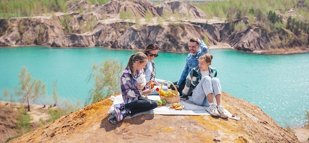 Panorama de familia joven en picnic después de caminar en las montañas Hermosa vista del lago azul