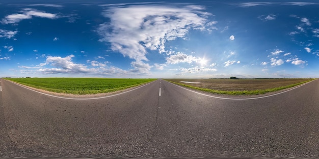 Panorama hdri sem costura esférico completo vista de ângulo de 360 graus em estrada de asfalto sem tráfego entre campos com céu azul claro em conteúdo VR AR de projeção equirretangular