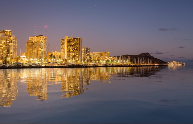 Panorama del horizonte nocturno de Honolulu y Waikiki desde el parque Ala Moana después de la puesta de sol con reflejo de agua artificial