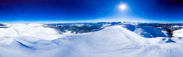 Panorama mágico de uma bela colina nas montanhas coberta de neve na pista de esqui em um dia ensolarado