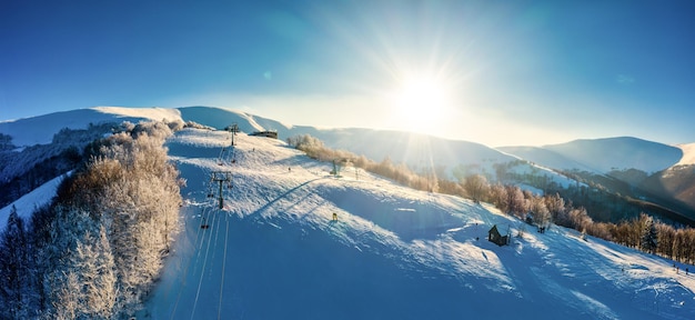 Panorama mágico do inverno de belas encostas nevadas em uma estação de esqui na Europa em um dia ensolarado e gelado sem vento. O conceito de recreação ativa no inverno