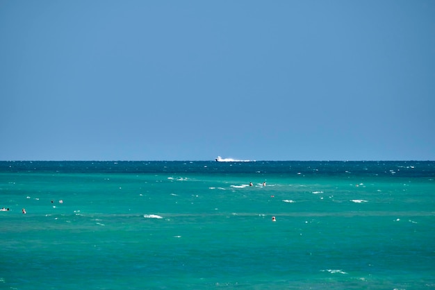 Panorama marítimo Pequeño barco a motor flota en aguas profundas de la bahía azul bajo edificios altos de un cielo azul brillante en la costa lejana