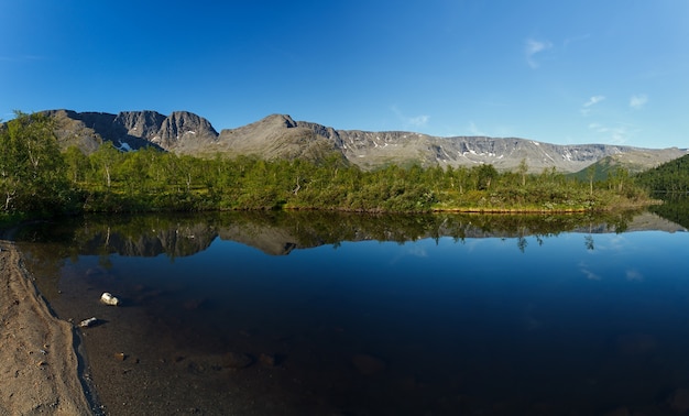 Foto panorama mit den bergen des khibiny, himmel spiegelt sich im see kleiner vudyavr. kola-halbinsel, russland.