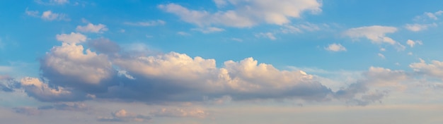 Panorama mit lockigen rosa Wolken auf einem blauen Himmel