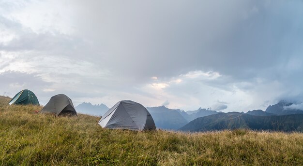 Panorama de las montañas, en un claro, hay tres carpas