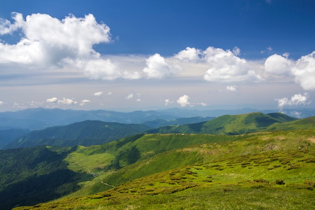 Panorama de las montañas verdes debajo del cielo azul en día soleado brillante.