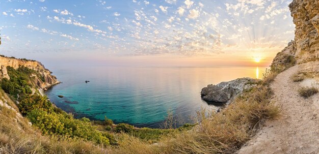 Panorama na hora do pôr do sol com belas nuvens na baía rochosa com mar azul cristalino em um