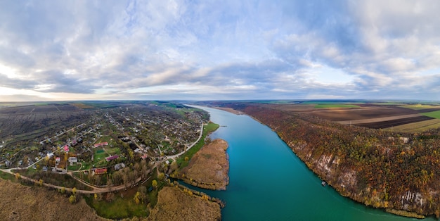 Panorama de la naturaleza en Moldavia. Dniéster con un pueblo al lado del río, campos que se extienden sobre el horizonte. Vista desde el dron