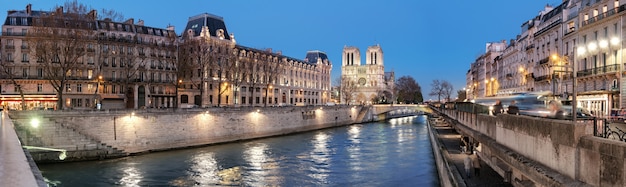 Panorama de noche de París iluminada y río Sena