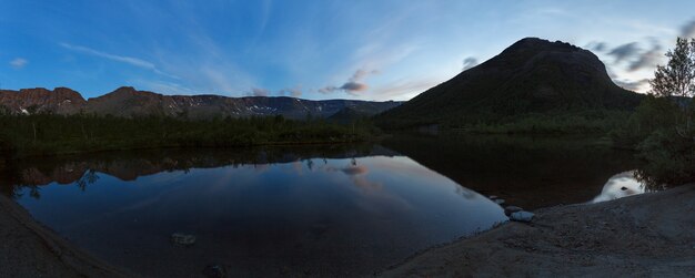 Panorama nocturno con las montañas del Khibiny, cielo reflejado en el lago Small Vudyavr. Península de Kola, Rusia.