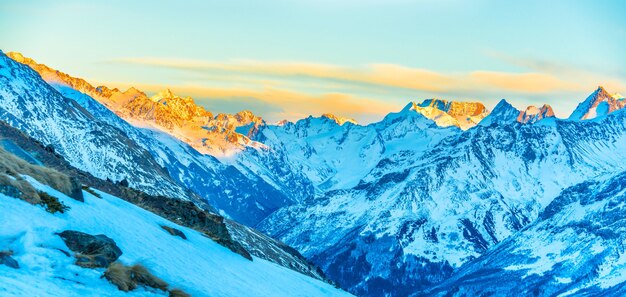 Panorama de picos nevados en la cordillera. Paisaje con cielo al atardecer y nubes.