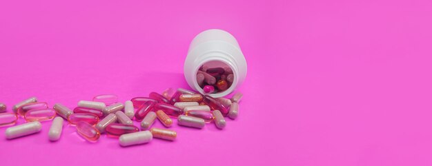 Panorama píldoras y cápsulas multicolores sobre un fondo rosa