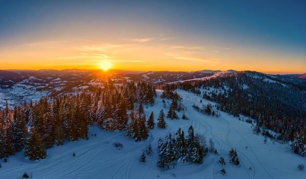 Panorama pitoresco do inverno das colinas cobertas de neve e abetos em um dia ensolarado e claro com o sol e o céu azul. Conceito de beleza da natureza intocada. Copyspace