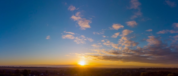 Panorama de la salida del sol. Cielo azul con nubes naranjas.