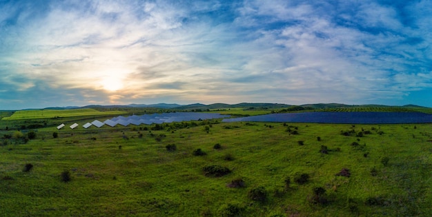 Panorama sobre paneles solares para generar energía a partir de los rayos del sol instalados en los prados bajo un cielo azul con sol