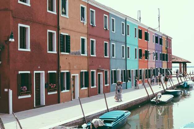 Panoramablick auf bunte Häuser und Wasserkanal mit Booten in Burano, einer Insel in der Lagune von Venedig. Sonniger Sommertag und blauer Himmel