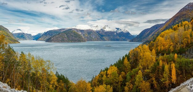 Panoramablick auf den norwegischen Fjord, Herbstwälder und ferne schneebedeckte Berge von oben