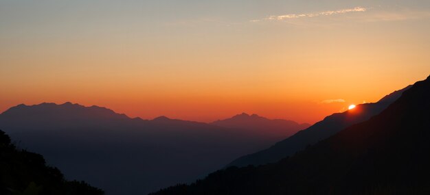 Panoramablick auf den roten und orangefarbenen Sonnenuntergang mit Sonnenuntergang in den Bergen