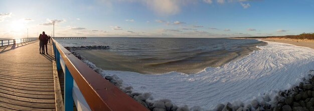 Panoramablick auf den Sandstrand der Brücke unter Schnee und Eiswellen der Ostsee an einem sonnigen Tag