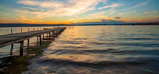 Panoramablick auf die atemberaubende Dämmerung am Ufer mit einem Holzsteg