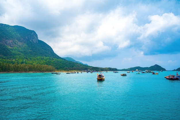 Panoramablick auf die Küste der Insel Con Dao von oben mit Wellen, klarem Himmel, straßenblauem Meer und Bergen