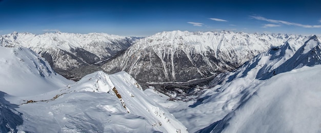 Panoramablick auf die schneebedeckten Berggipfel im blauen Himmel der Wolken Kaukasus