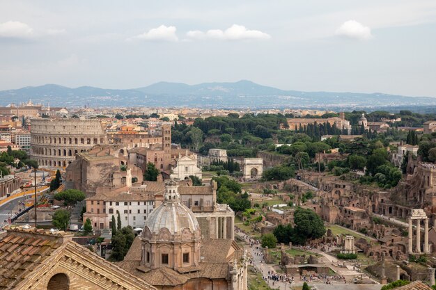 Panoramablick auf die Stadt Rom mit Forum Romanum und Kolosseum von Vittorio Emanuele II Monument auch bekannt als Vittoriano. Sonniger Sommertag und dramatischer blauer Himmel