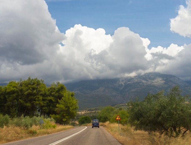 Panoramablick auf die Straßenwaldberge und Felder ein Sommersturm mit schwarzen Wolken in Griechenland