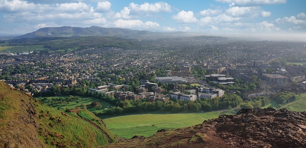 Panoramablick auf Edinburgh von einem Hügel. Grün, Hügel, Gebäude, Meer in der Ferne