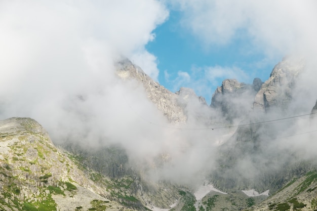 Panoramablick auf felsige Berge, die mit flauschigen Wolken bedeckt sind