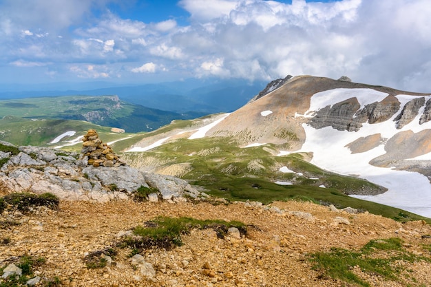 Foto panoramablick auf idyllische hügel, landschaft mit blühenden wiesen und schneebedeckten alpinen berggipfeln im hintergrund an einem wunderschönen sonnigen tag