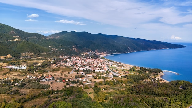 Panoramablick auf Stratonion von der Drohne, mehrere Gebäude auf Ägäis kosten, Hügel bedeckt mit üppigem Grün, Griechenland