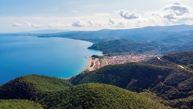 Panoramablick auf Stratonion von der Drohne, mehrere Gebäude auf Ägäis kosten, Hügel bedeckt mit üppigem Grün, Griechenland