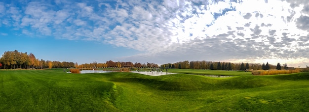 Panoramablick auf Teich und grüne Wiese im Herbstpark. Oktober Wald und See, Naturlandschaft am sonnigen Tag