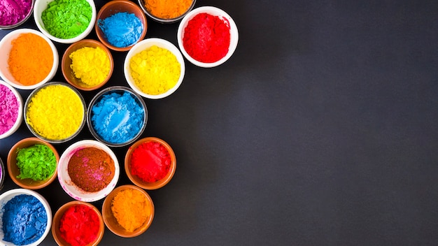 Panoramablick des holi Farbpulvers in den Schüsseln auf schwarzem Hintergrund