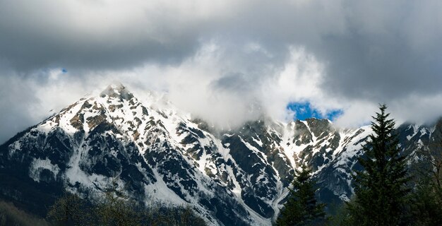 Panoramablick des schneebedeckten Gebirgskamms in den Wolken