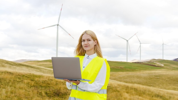 Foto panoramafoto einer weiblichen stromnetzingenieurin mit laptop vor dem hintergrund von windturbinen erneuerbare energie