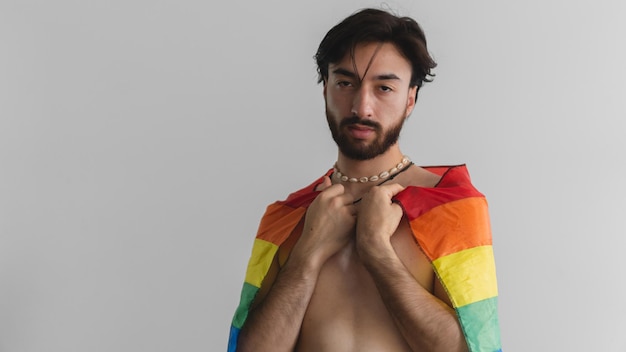 Panoramafoto eines jungen lateinamerikanischen Queer-Mannes mit lgtb-Flagge auf dem Rücken auf weißem Hintergrund Kopierbereich