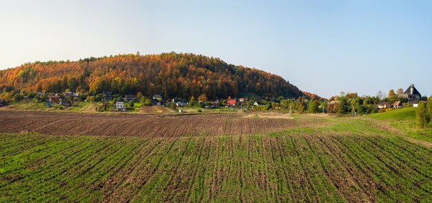 Panoramalandschaft mit Ackerland, im Hintergrund ein Hügel und ein Dorf.