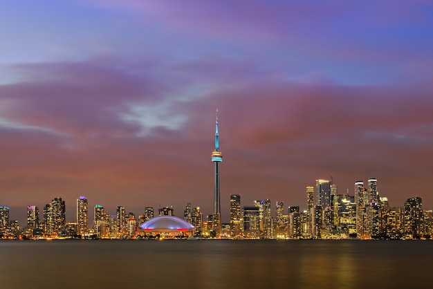 Panorámica del paisaje urbano iluminado del centro de Toronto sobre el lago Ontario en penumbra, Toronto, Canadá